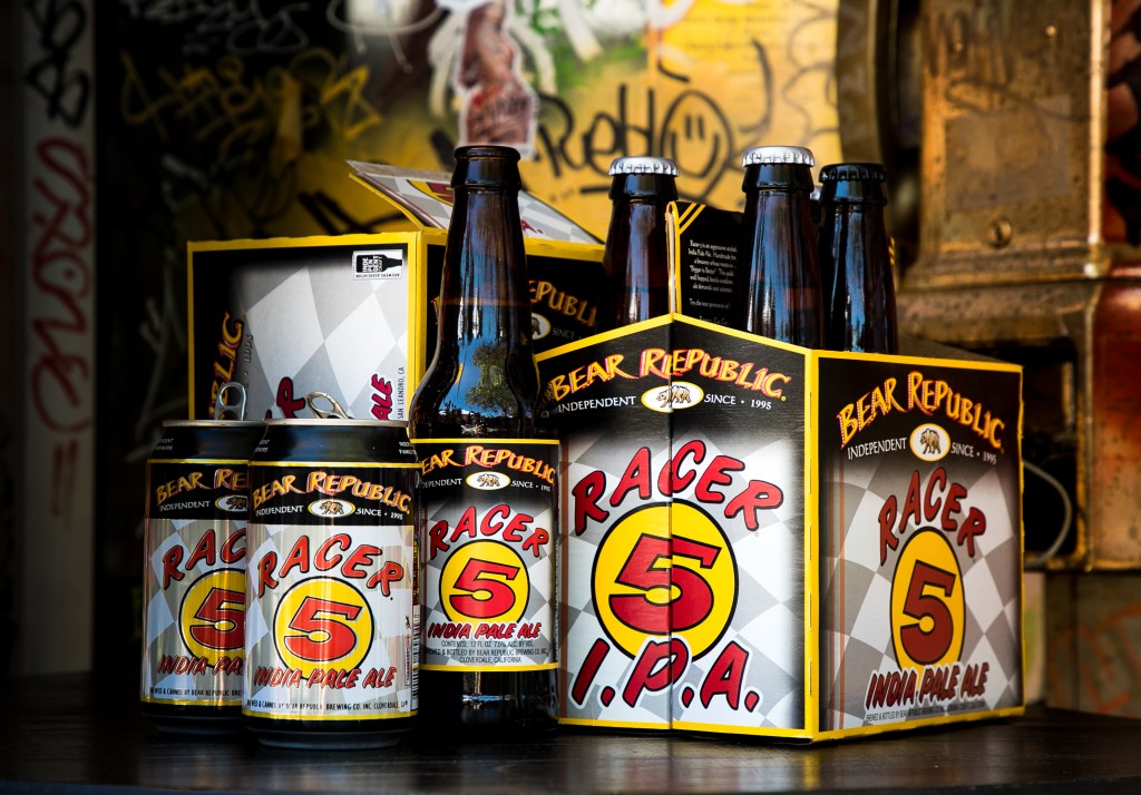 Bear Republic Racer 5 IPA six-packs and glass bottles arranged against a graffiti-style backdrop.
