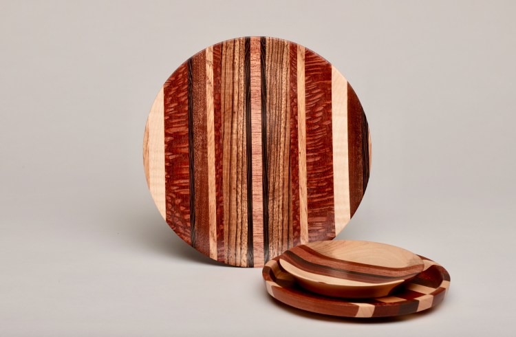 set of handcrafted round wooden plates with varying striped patterns in natural and reddish tones.